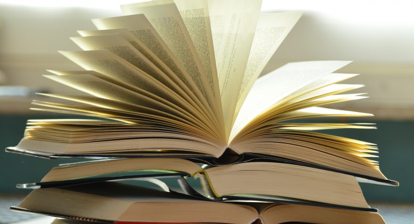 Åpnet bok oppå bokhaug