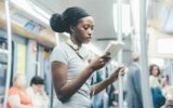 Kvinne leser en bok mens hun står på en buss