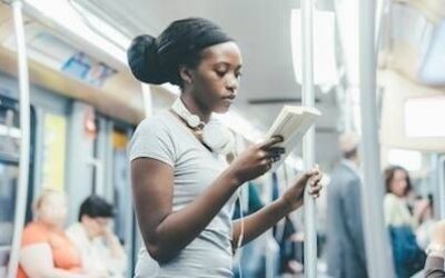 Kvinne leser en bok mens hun står på en buss