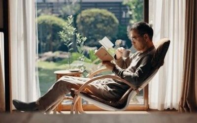 Person leser en bok i en lenestol med en kopp te ved vinduet